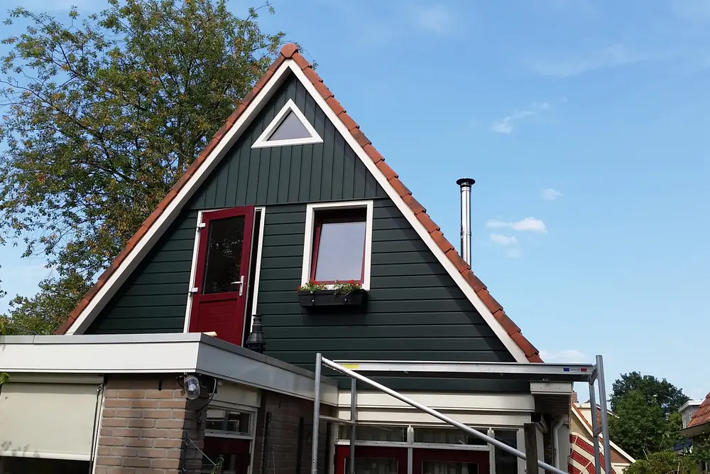 Opgeleverde uitbreiding van de eerste verdieping in Heerenveen, met donkergroene gevelbekleding en een rode deur